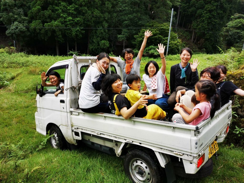 A group of people happily riding a small truck